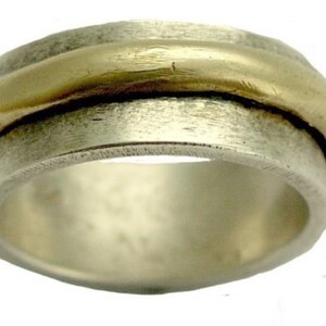 May include: A silver and gold spinning ring with a textured finish. The ring is made of two bands, one silver and one gold, that spin independently.