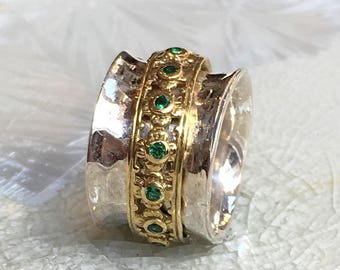 May include: A silver and gold ring with a band of green gemstones. The ring is textured and has a hammered finish.