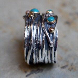 May include: A silver ring with a textured, woven design. The ring is adorned with turquoise and gold accents.