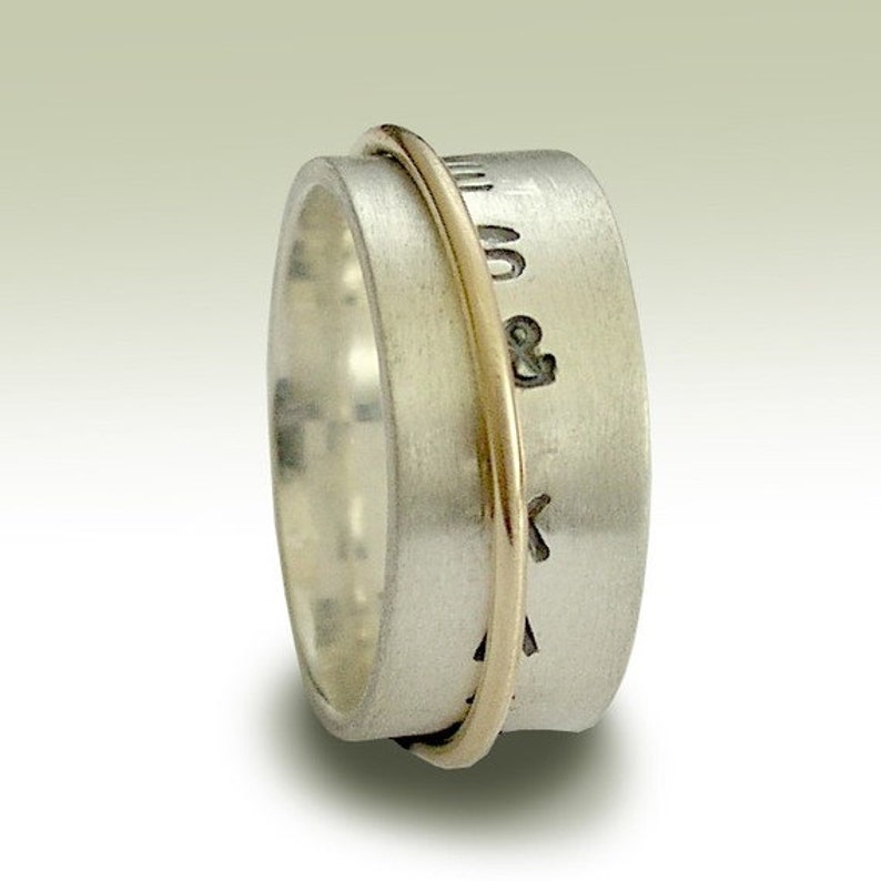 May include: A silver spinning ring with a gold band. The ring has the words "Mum & Dad" engraved on it.