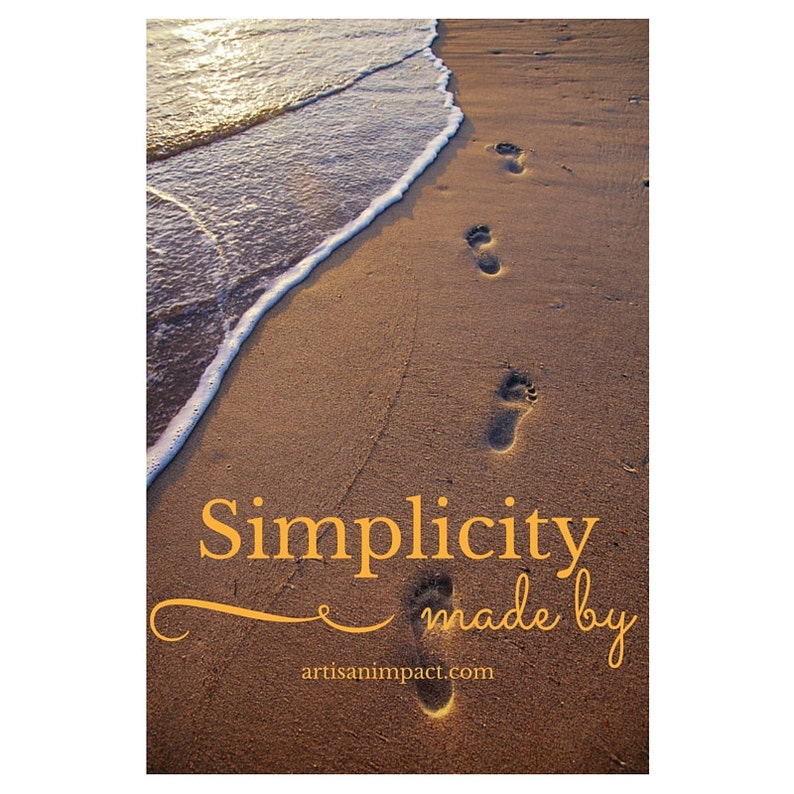 May include: A photograph of a sandy beach with footprints leading towards the ocean. The text "Simplicity made by artisanimpact.com" is displayed in a golden color, adding a touch of elegance to the scene.