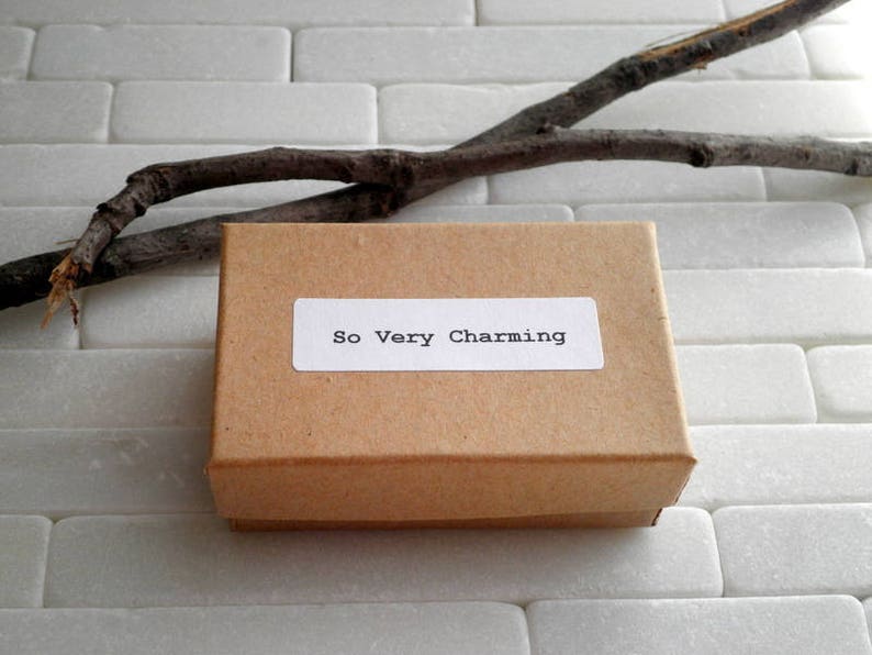 May include: A brown cardboard box with a white label that says "So Very Charming".