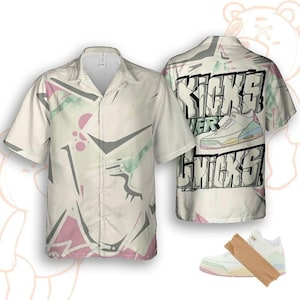 Könnte beinhalten: Kurzärmeliges Button-Down-Hemd mit cremefarbenem Hintergrund und abstrakten geometrischen Formen in Grau, Rosa und Grün. Auf der Rückseite des Hemdes steht der Text "Kicks Over Chicks" mit einer Sneaker-Grafik. Unten ist ein Sneaker abgebildet.