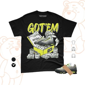 Pode incluir: Camiseta preta com o texto "GOT'EM" em amarelo. O gráfico apresenta um par de tênis em uma caixa amarela com dinheiro e o número 23. A marca "NASTYJAMZ" está no topo.