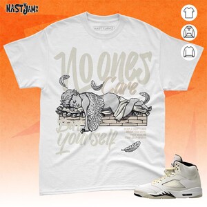 May include: White t-shirt with a graphic of a sleeping angel on a pile of money. The text "No one cares but yourself" is written in a stylized font. The text "People don't care about you until they realize your self-worth" is also included.