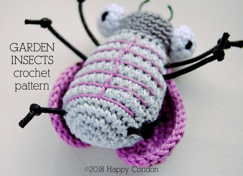 Op de afbeelding: Een gehaakt grijs en roze insect met zwarte poten en witte ogen. Het insect zit op een roze gehaakte basis. De tekst "GARDEN INSECTS crochet pattern" is zichtbaar in de afbeelding.