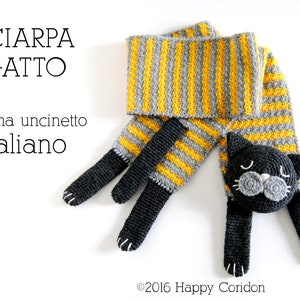 May include: A crocheted cat scarf with yellow and gray stripes. The scarf has a cat's head and two paws on each end. The text "SCIARPA GATTO schema uncinetto italiano" is visible in the image.