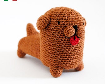 Può includere: Un giocattolo per cani in crochet marrone con la lingua rossa che sporge. Il giocattolo ha gli occhi neri e un naso marrone.