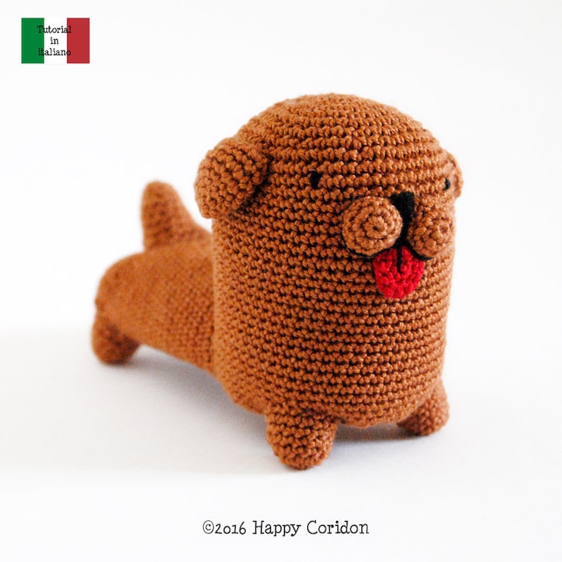 May include: A brown crocheted dog toy with a red tongue sticking out. The toy has black eyes and a brown nose.