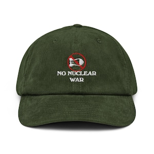 May include: Olive green corduroy baseball cap with the embroidered text "NO NUCLEAR WAR" and a graphic of a bomb crossed out. The cap has a curved brim and a structured crown.