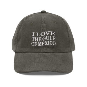 May include: A dark green corduroy baseball cap with white embroidered text that reads "I LOVE THE GULF OF MEXICO".