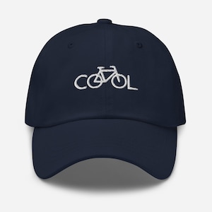 Puede incluir: Una gorra de béisbol azul marino con bordado blanco de una bicicleta y la palabra "COOL".