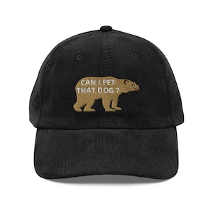 May include: Black corduroy baseball cap with the embroidered phrase "CAN I PET THAT DOG?" above a tan bear silhouette. The cap has a curved brim and an adjustable strap for a comfortable fit. A fun and casual accessory.