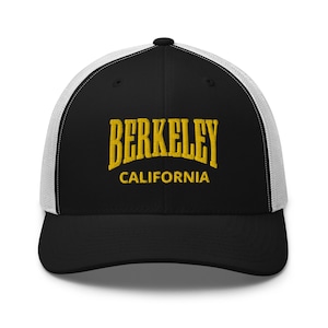May include: Black and white trucker hat with a black front panel and a white mesh back. The front panel features a gold embroidered logo that says "BERKELEY CALIFORNIA".