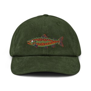 May include: A green corduroy baseball cap featuring an embroidered image of a trout fish. The fish is orange, green, and blue with black spots.