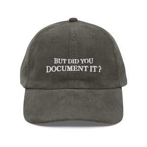 Puede incluir: Gorra de béisbol de pana verde oliva con el texto bordado en blanco "BUT DID YOU DOCUMENT IT?". La gorra tiene una visera curva y una parte superior redondeada.