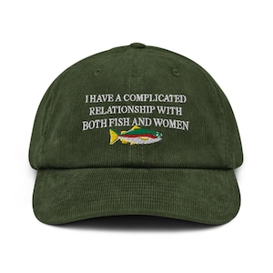 May include: A dark green corduroy baseball cap with the embroidered text "I HAVE A COMPLICATED RELATIONSHIP WITH BOTH FISH AND WOMEN" above a colorful fish graphic. The cap has a curved brim and an adjustable strap.