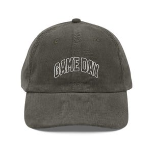 May include: A green corduroy baseball cap with white embroidered text that reads "GAME DAY".