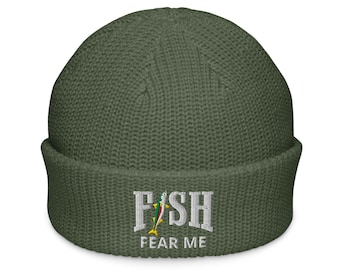 May include: Olive green beanie with the embroidered text "FISH FEAR ME" in white. The word "FISH" has a colorful fish graphic. The beanie is made of a ribbed knit material.