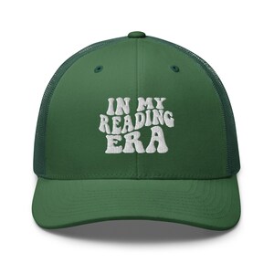 Op de afbeelding: Een groene truckercap met een wit geborduurd ontwerp dat "In My Reading Era" zegt.