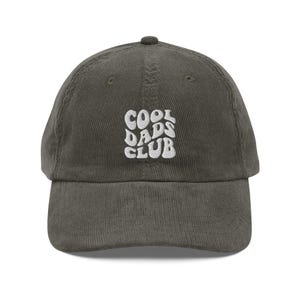 Peut inclure: Une casquette de baseball en velours côtelé vert foncé avec un texte brodé blanc qui dit "Cool Dads Club" dans une police rétro.