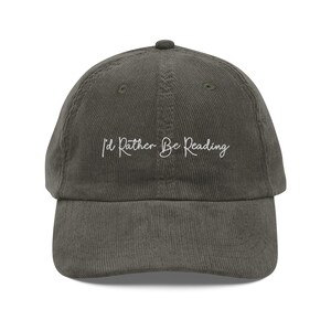 Peut inclure: Une casquette de baseball en velours côtelé vert foncé avec un texte brodé blanc qui dit "I'd Rather Be Reading".