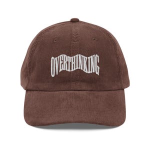 May include: A brown corduroy baseball cap with white embroidery that reads "OVERTHINKING".