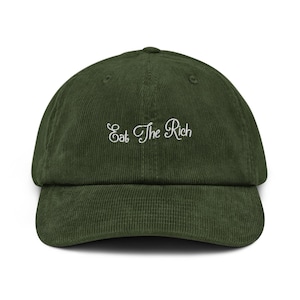 Könnte beinhalten: Dunkelgrüne Cord-Baseballkappe mit gebogenem Schirm. Der Schriftzug "Eat The Rich" ist in weißer Schreibschrift auf die Vorderseite gestickt. Die Kappe hat eine strukturierte Krone und einen verstellbaren Riemen.