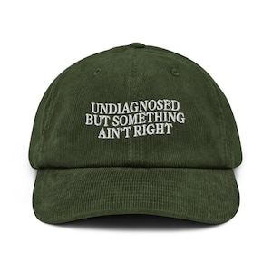 May include: A green corduroy baseball cap with white embroidered text that reads "Undiagnosed but something ain't right."