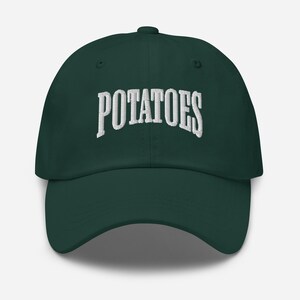 May include: A dark green baseball cap featuring the word "POTATOES" embroidered in white. The cap has a curved peak and an adjustable strap. The hat is made of a soft fabric and is a casual accessory.