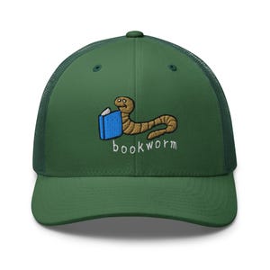 Op de afbeelding: Een groene en zwarte mesh trucker cap met een geborduurd beeld van een worm die een boek leest. De tekst "bookworm" is onder het beeld geborduurd.