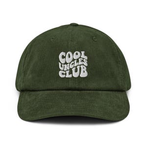 Puede incluir: Gorra de béisbol de pana verde oscuro con el texto "COOL UNCLES CLUB" bordado en blanco. La gorra tiene una visera curva y una corona estructurada. Es un accesorio informal.