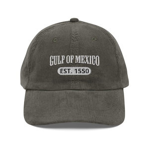 Puede incluir: Una gorra de béisbol de pana verde oscuro con texto bordado en blanco que dice "GULF OF MEXICO EST. 1550".