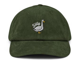 May include: A dark green corduroy baseball cap with a curved brim. The cap features an embroidered design of a goose and the word "Silly" in white script. The goose has a white body, gray wings, and yellow feet and beak.