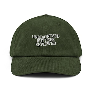 Può includere: Cappellino da baseball in velluto a coste verde scuro con la scritta ricamata bianca «UNDIAGNOSED BUT PEER REVIEWED». Il cappellino ha una visiera curva e una corona arrotondata, adatta all'uso casual.