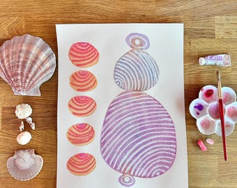 Könnte beinhalten: Eine künstlerische Komposition mit einem Aquarellgemälde abstrakter, gestreifter Formen in Rosa- und Lilatönen. Muscheln verschiedener Größen und Farben sind neben dem Gemälde angeordnet. Eine Palette mit Farbe und einem Pinsel ist ebenfalls vorhanden.