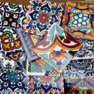 May include: A collection of colorful, patterned ceramic tiles. The tiles feature floral and geometric designs in shades of blue, red, orange, and green. Some tiles have a glossy finish, while others appear matte.