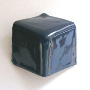 May include: A dark blue, square-shaped object with a slightly rounded top. The object has a glossy finish and appears to be made of a solid material. The background is plain white.