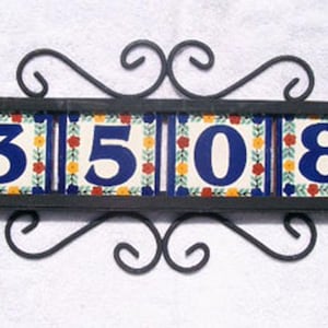 May include: Decorative address plaque featuring the numbers "3508" in blue on colorful ceramic tiles. The tiles are set in a black metal frame with decorative scrollwork. A charming addition to any home.