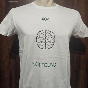 Può includere: Maglietta bianca con una grafica di cervello nero e il testo "404 NOT FOUND" in verde.