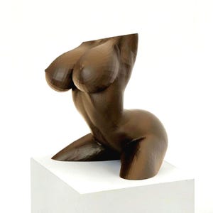 May include: A dark brown, faceted sculpture of a human torso. The figure is depicted in a kneeling position with a smooth, geometric surface texture that creates distinct angular planes across the chest, waist, and hip areas of the form.