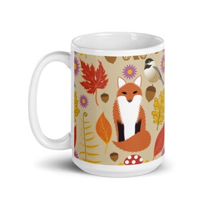 Puede incluir: Taza de cerámica blanca con un patrón colorido de un zorro, hojas, setas y pájaros. El patrón se repite en la taza.