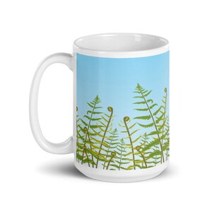 May include: White ceramic mug featuring a design of green ferns against a light blue background.