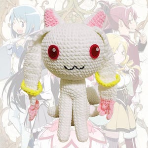 May include: A white crocheted plush toy featuring long ears with pink inner accents, bright red circular eyes, and a small black stitched mouth. The figure has yellow rings around its ears and pink tips, with a soft, textured yarn construction.