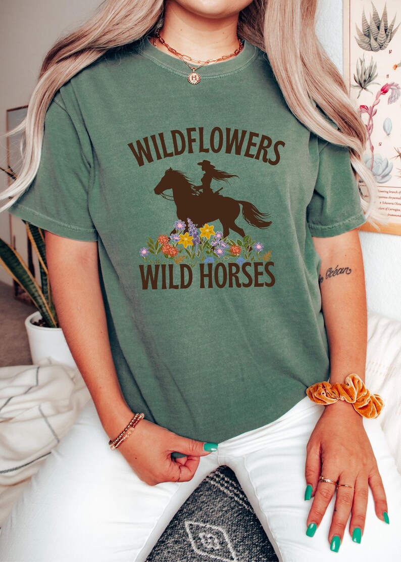 May include: A green t-shirt with the text "Wildflowers Wild Horses" and a silhouette of a woman riding a horse with flowers around the horse.
