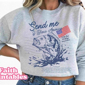 May include: A light grey sweatshirt featuring a blue graphic of a fish leaping from water, an American flag, and the text "Send me & Bless America". The sweatshirt also has the text "With God all things are possible".
