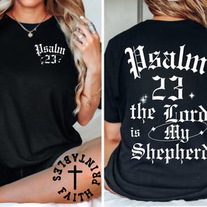 May include: Black t-shirt with the text "Psalm 23" in white gothic font on the front and back. The back of the shirt also features the phrase "the Lord is My Shepherd" in a similar font, with star accents.