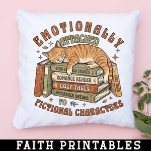 May include: White square pillow with a sleeping orange tabby cat on a stack of books. The books have titles like "Romance Reader" and "Cozy Tales." Text reads "Emotionally Attached to Fictional Characters."