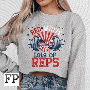 Może przedstawiać: Szara bluza z patriotycznym wzorem. Grafika przedstawia sztangę z czerwoną, białą i niebieską kokardą, słowa "RED WHITE" powyżej i "and LOTS OF REPS" poniżej. Gwiazdy i paski dopełniają projekt.