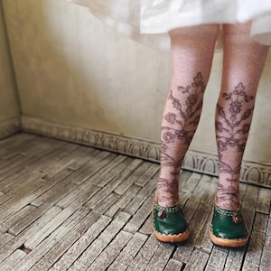 May include: A pair of dark green leather shoes with a floral pattern on the stockings. The shoes have a buckle on the front and a wooden heel.